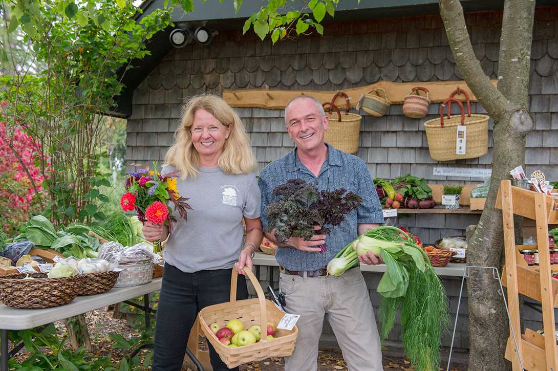 blond woman and man holding produce in front of shelburne farms farm store