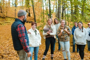 ABCs of Farm Based Education participants stand in fall forest listening to educator Jed Norris