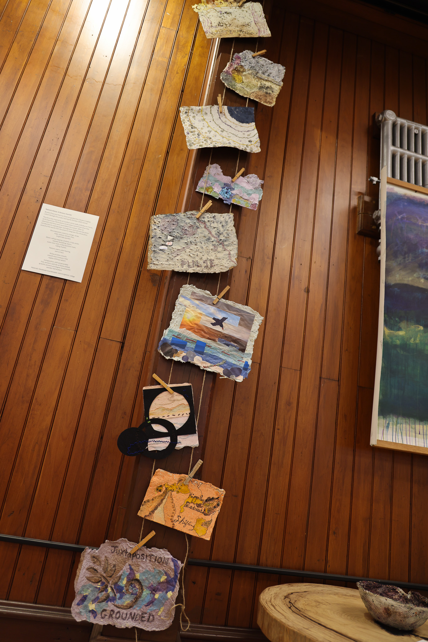 A variety of handmade papers hang on a wooden column