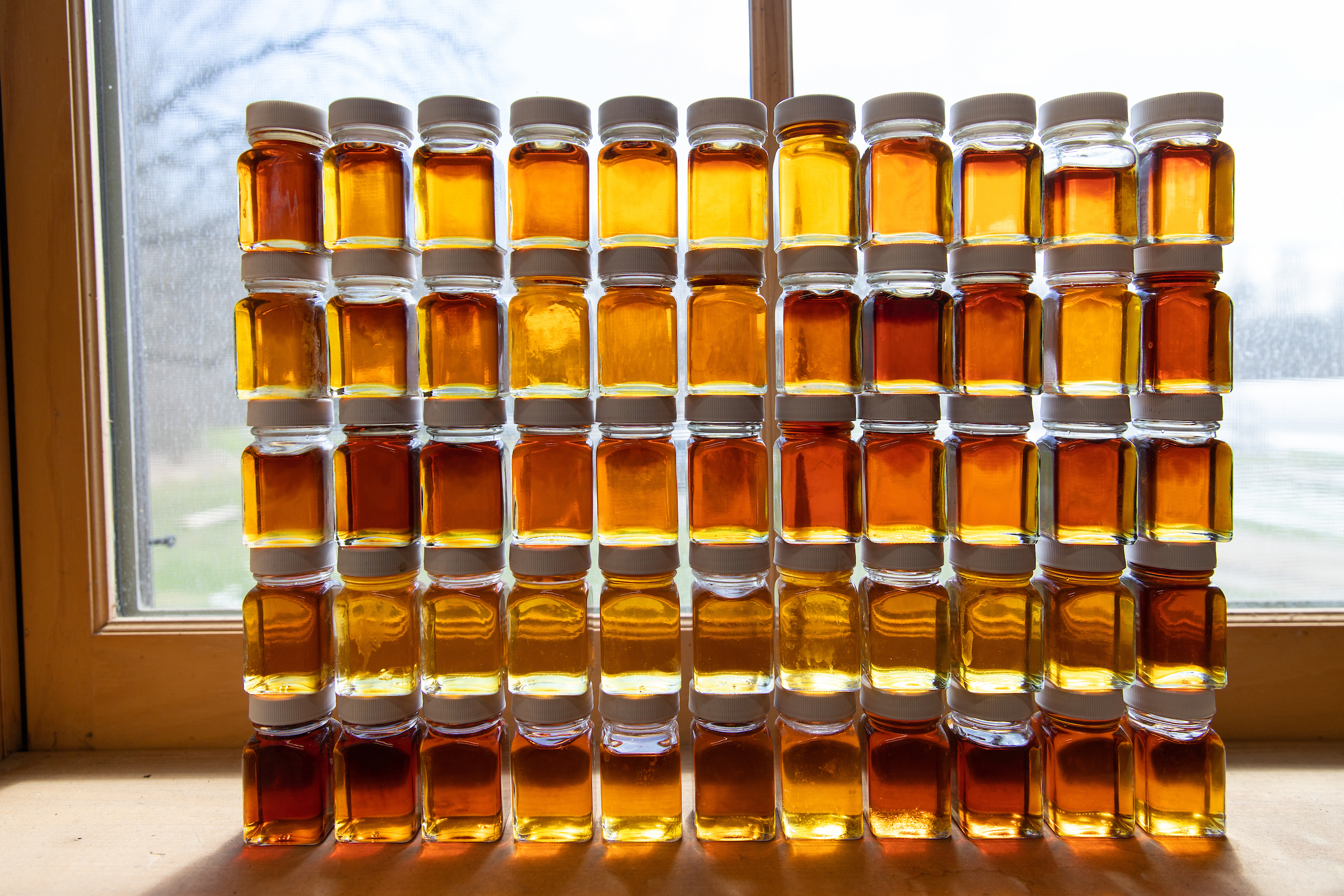 stacked sample bottles of maple syrup in a window