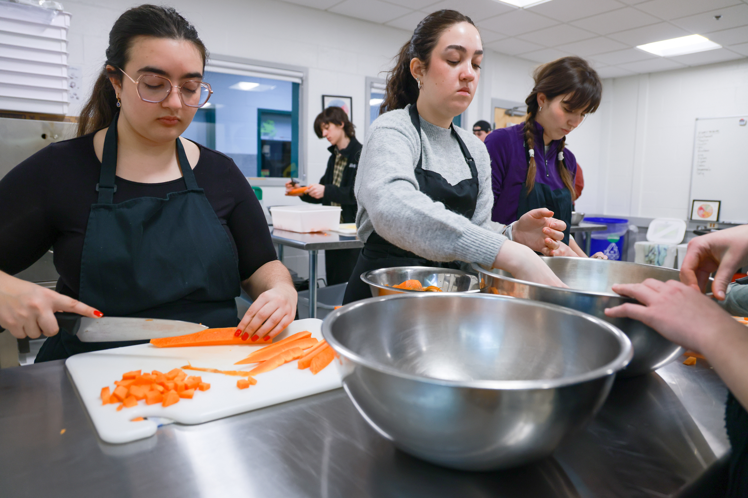 Students prepare carrots in an education kitchen.