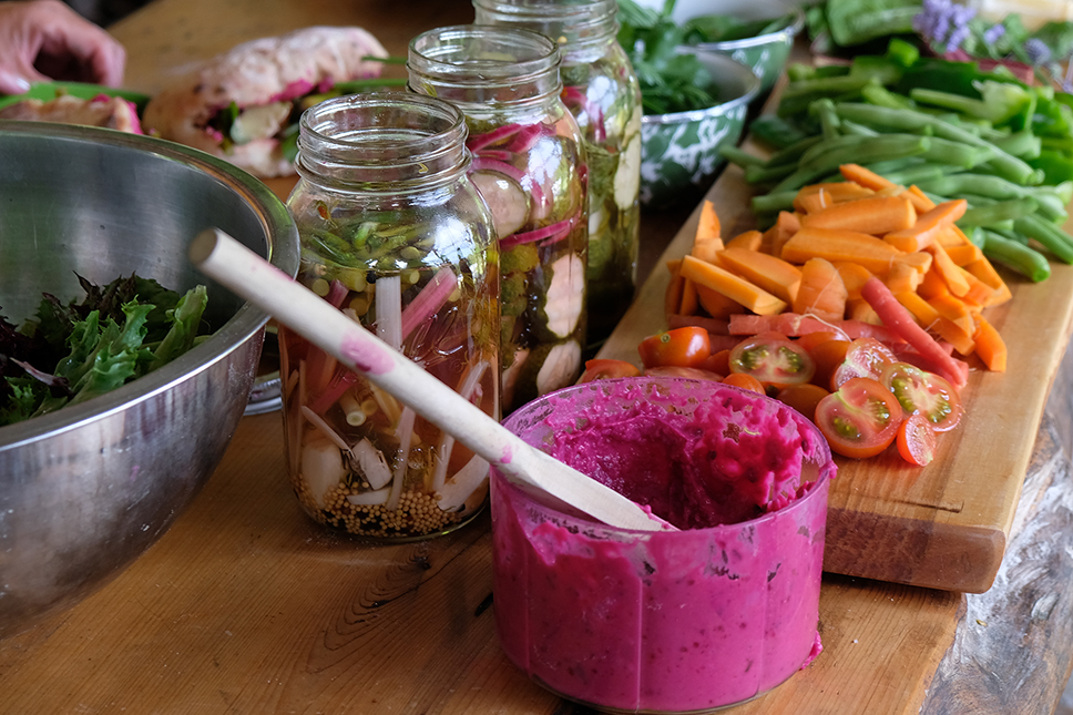 Bright red beet dip and assorted vegetables displayed on an outdoor wooden table