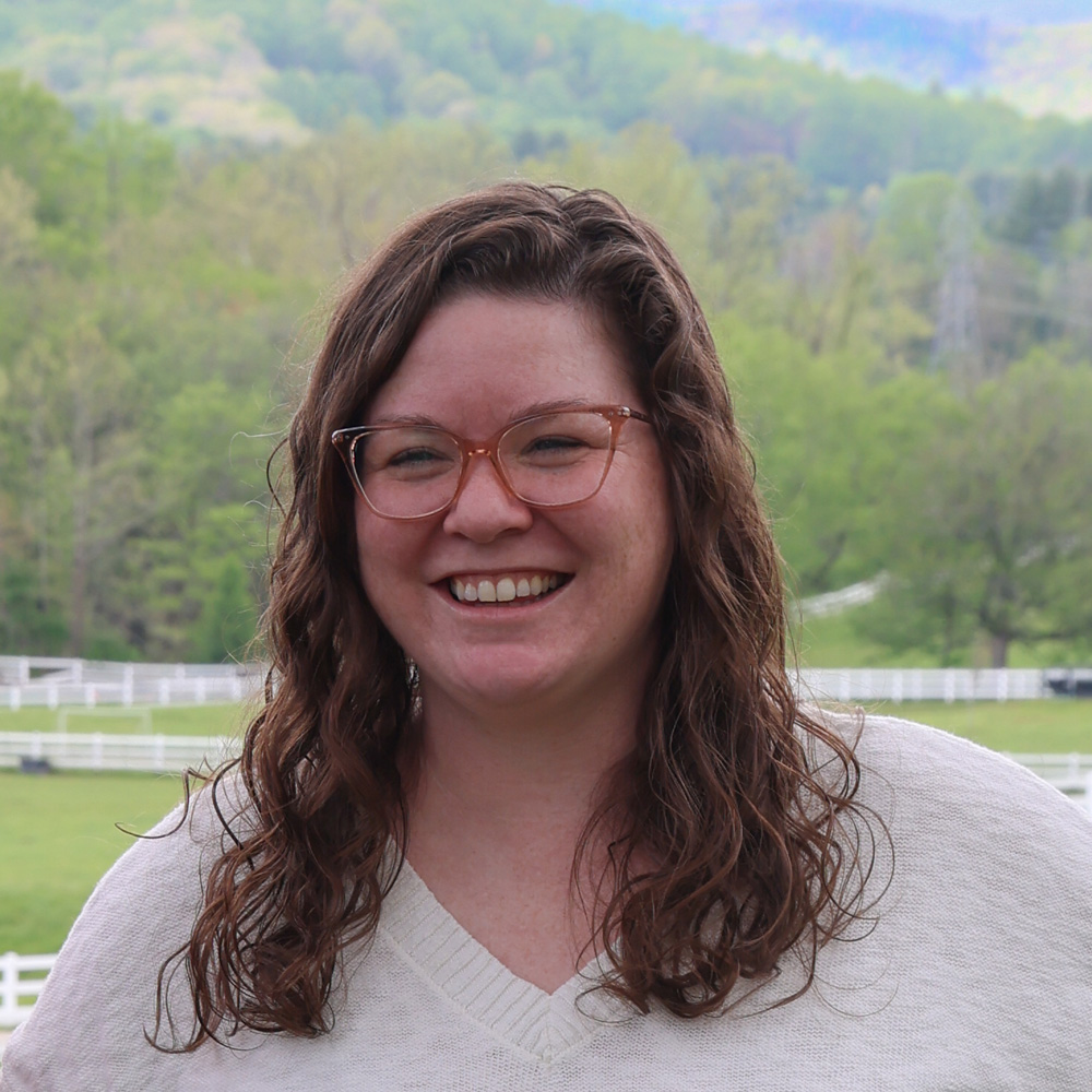 Casey smiling, trees and rolling hills in the background