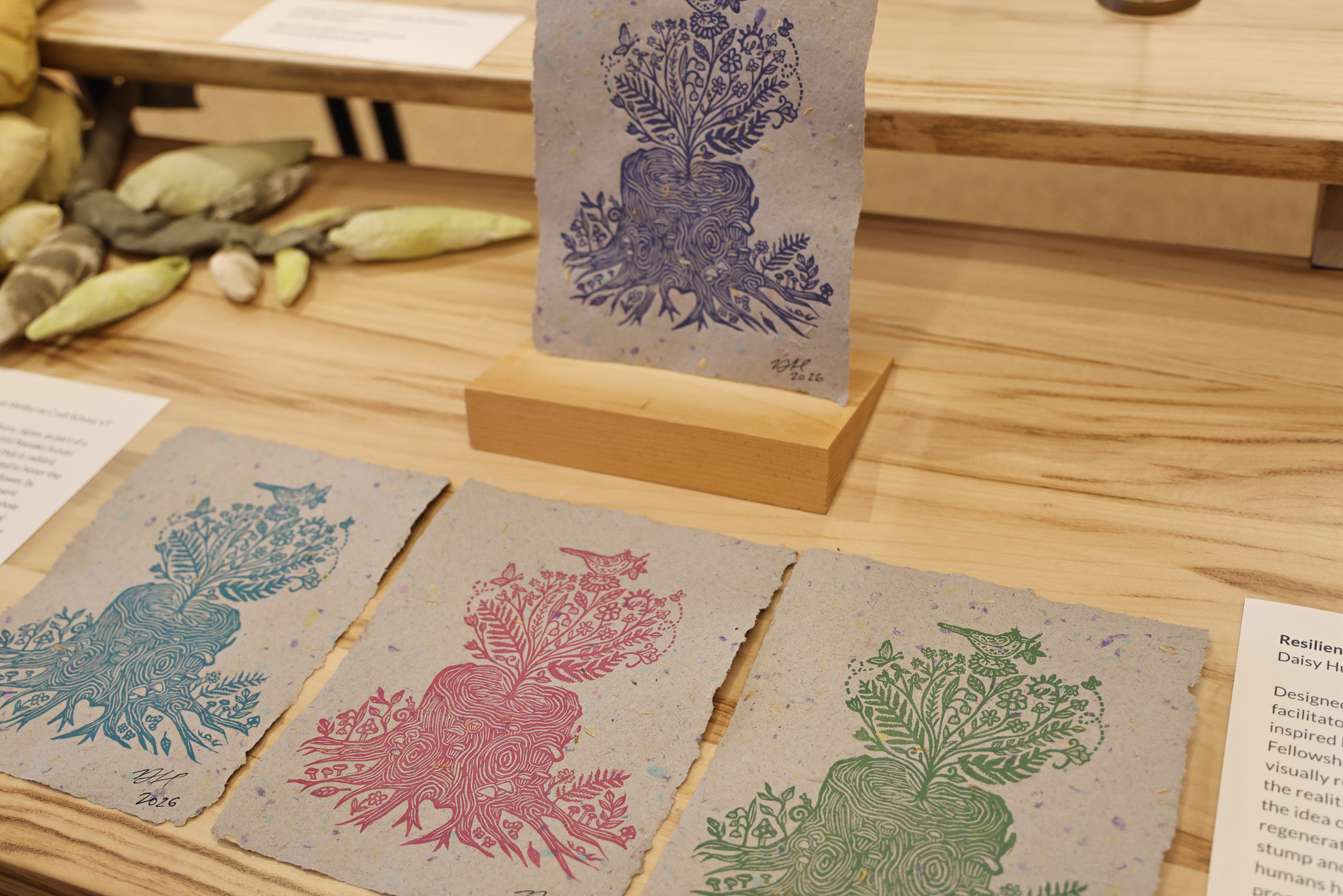 Hand carved linocut prints in various colors depicting plants blooming out of a tree stump