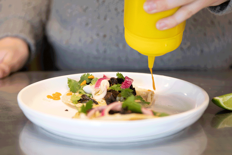 a GIF showing hot sauce being poured on top of a taco.