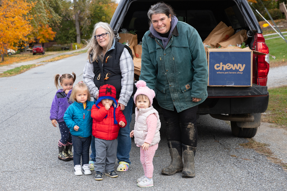 Two adults and four young kids stand in front of a farm truck