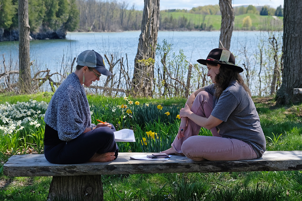 Two people sit facing each other on a bench in springtime, deep in conversation