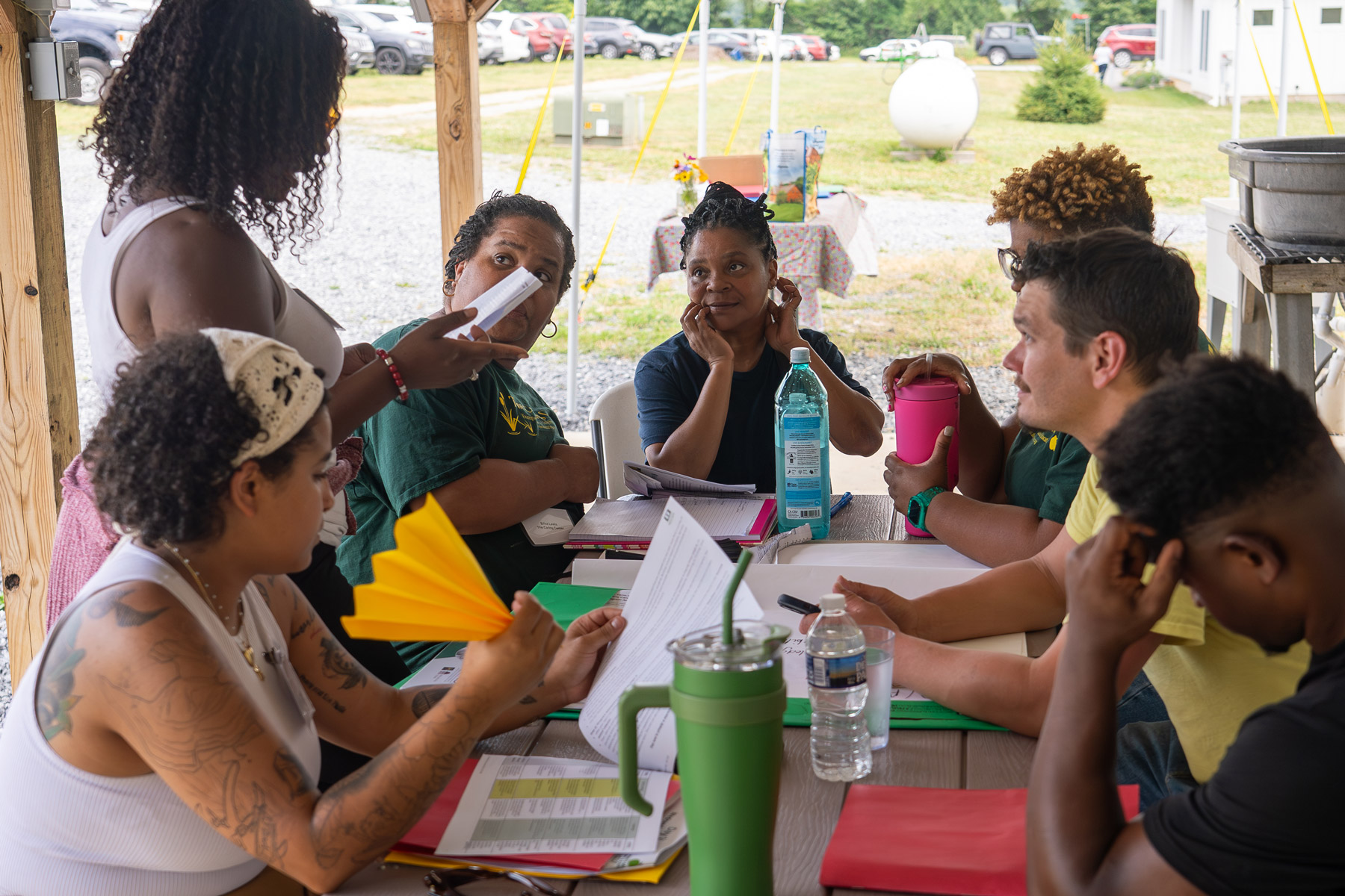 Group of people engaged in a discussion at an outdoor table.