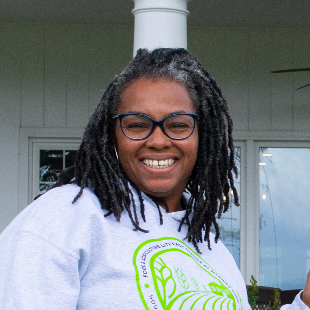 Phyllicia, smiling in front of an outdoor porch
