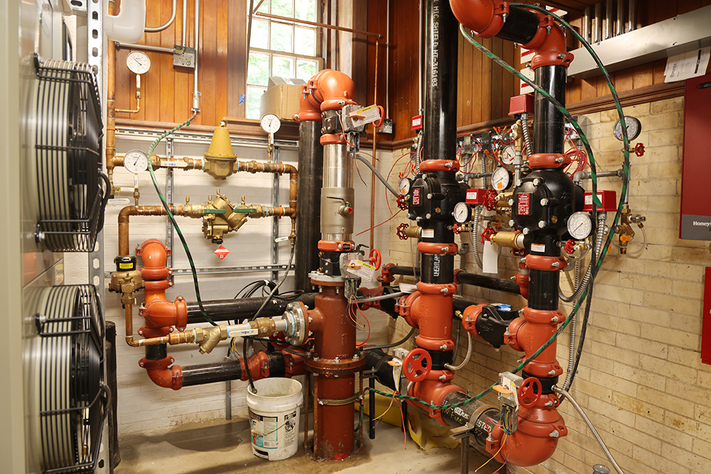 small room full of plumbing pipes and headers and gauges