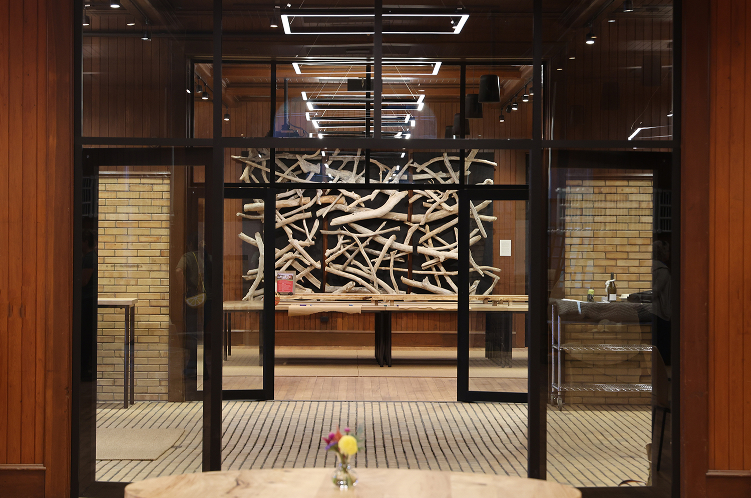 looking through two sets of wide doors into a hall that has driftwood hanging on thefar wall