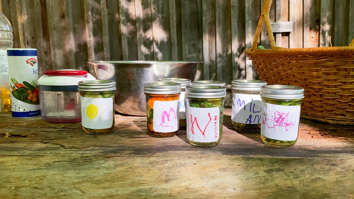 Jars of pickles on a table, their labels decorated by children