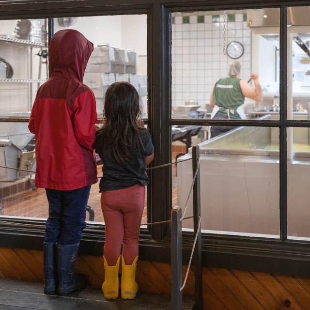 two girls watching cheese being made