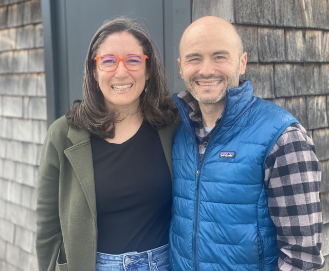 woman and man side by side. Woman has shoulder length dark hair and glasses. Man is bald, wearing flannel shirt and blue outdoor vest.
