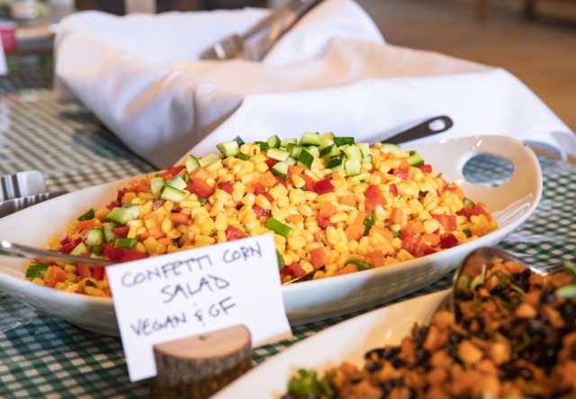 ​  A serving bowl of Confetti Corn Salad on a buffet line.