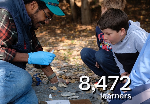 teacher with beard and glasses with student looking closely at a rock