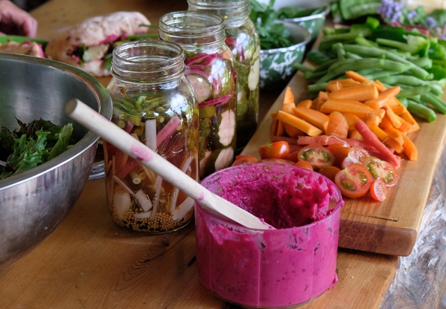 Bright red beet dip and assorted vegetables displayed on an outdoor wooden table