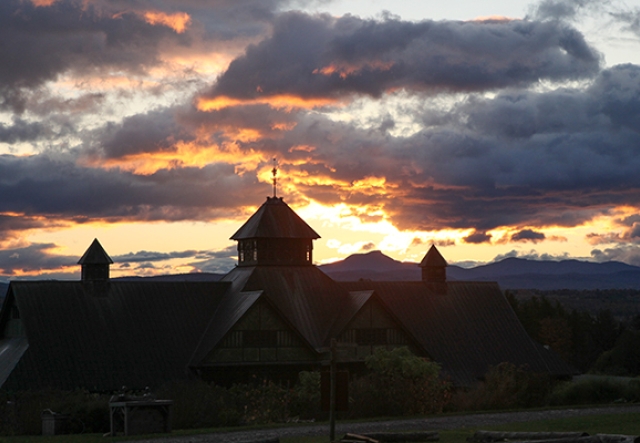 sun rising and reflecting on dark clouds with Farm Barn silhouetted in foreground