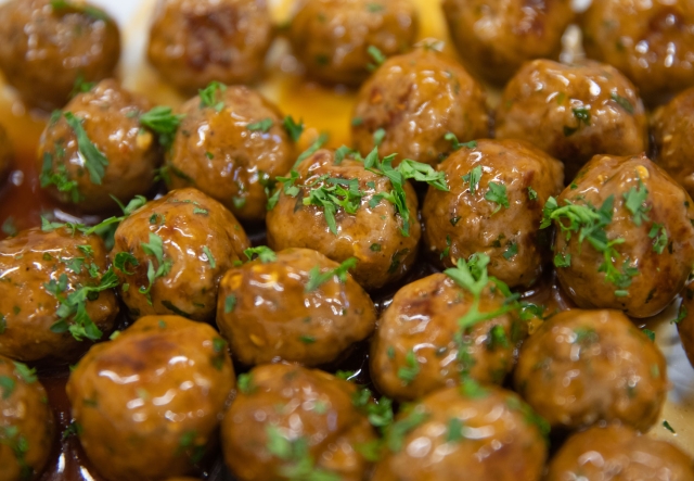 Close-up of glazed meatballs garnished with chopped parsley.
