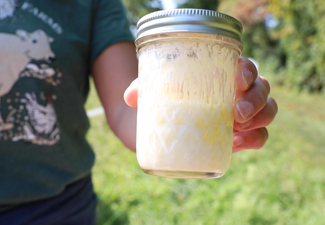 A youth hold a jar of butter in the making