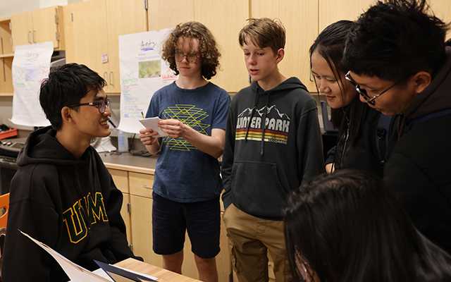 A group of young people gather around a table in a middle school laboratory