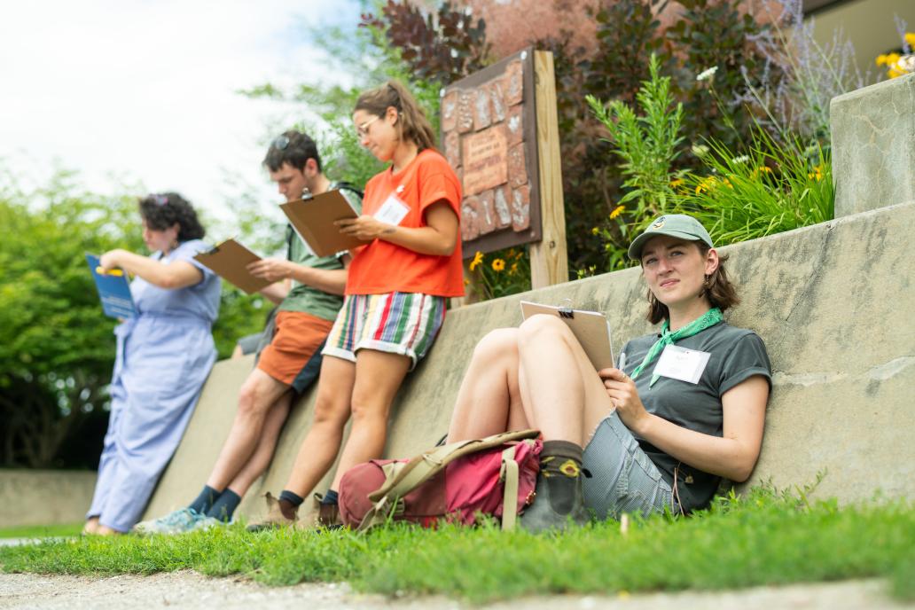 Educators sit outdoors, reading and writing