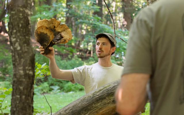 Ari Rockland-Miller holding up a large foraged mushroom