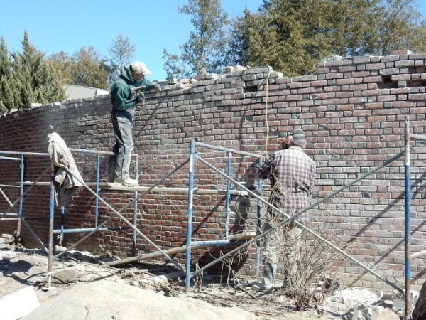 Masons repoint the pergola wall in March 2015, renewing the visible mortar joints between the bricks. (Rosalyn Graham)
