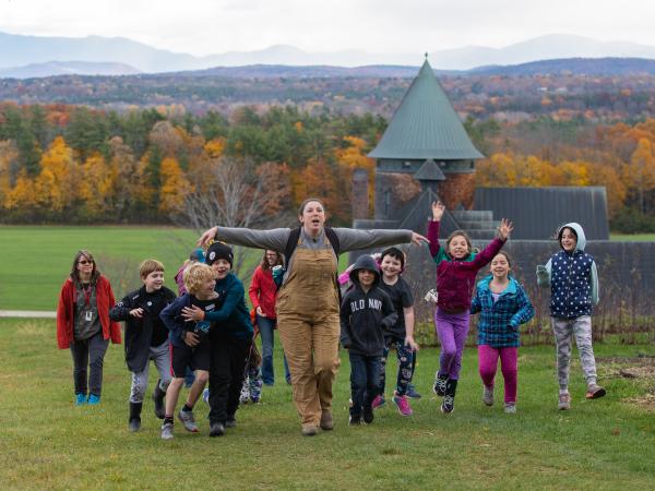 Educator leading children up behind the Farm Barn with tower in background