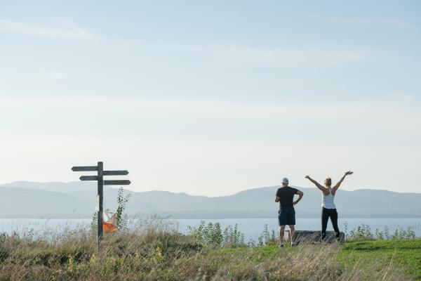 Two people enjoying the view from Lone Tree Hill across Lake Champlain to the Adirondacks
