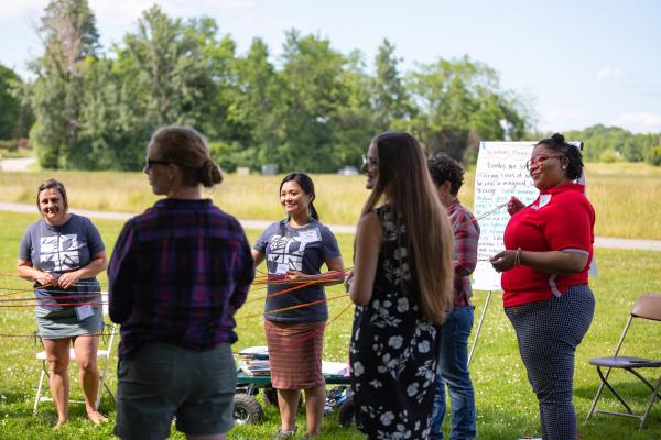 Education staff and participants create a food systems web during the 2022 Northeast Farm to School Institute Summer Retreat on the Coach Barn Lawn.