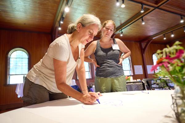 two educators writing on a flipchart on a table