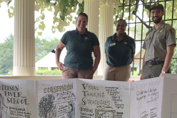A teacher and two NPS staff stand behind a brochure, created in an educator professional learning workshop