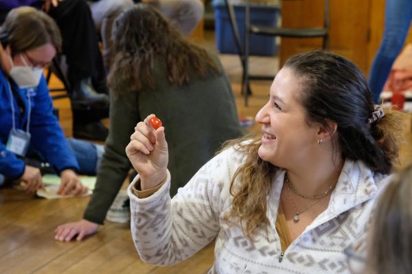 Educator smiles holding a cherry tomato
