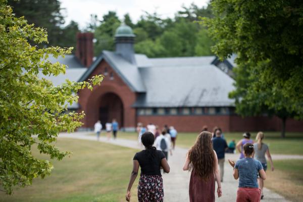 Three educators walk along a trail on Shelburne Farms' campus in summer