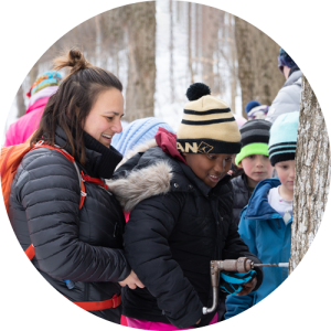 Shelburne Farms educator Courtney Mulcahy taps maple tree in winter with student