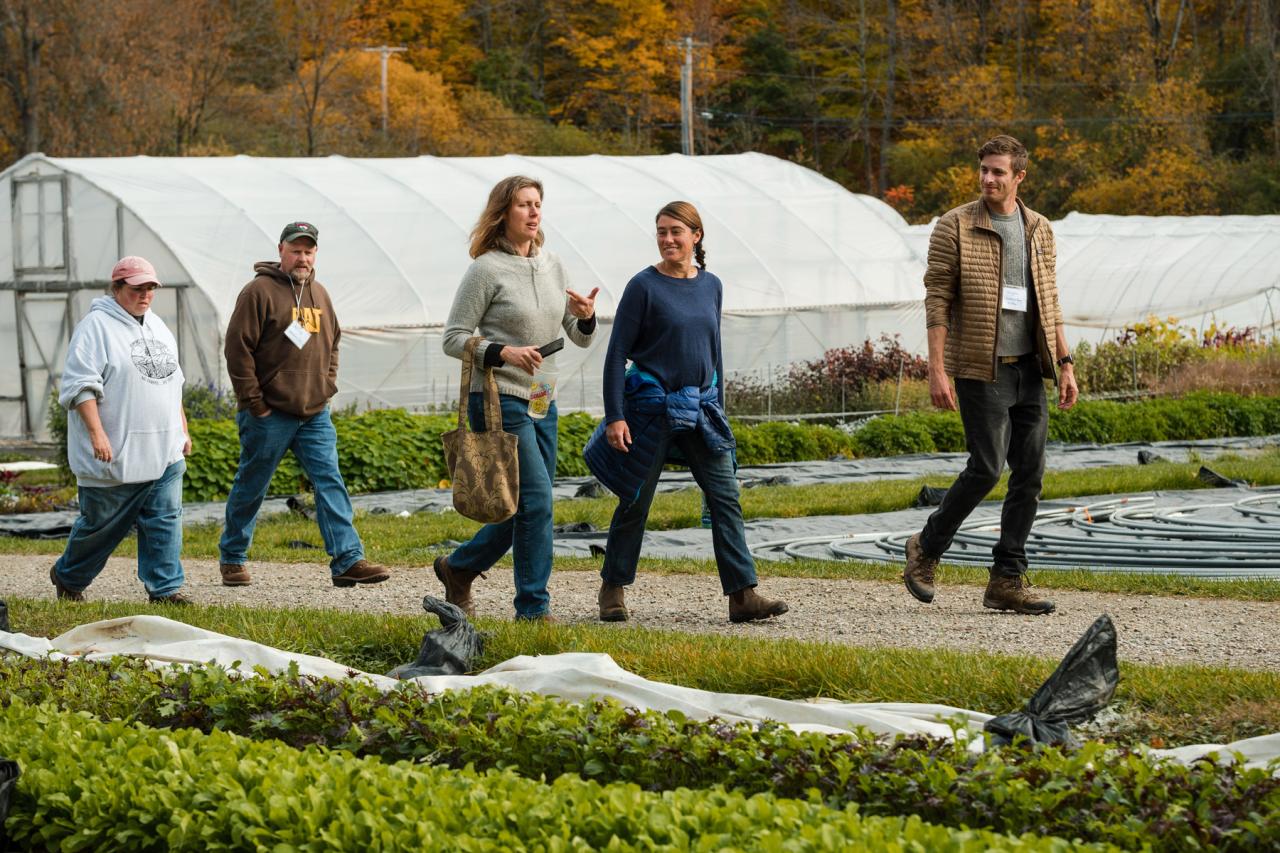 Participants walk along a trail in the Shelburne Farms Market Garden, hoop houses in the background. 