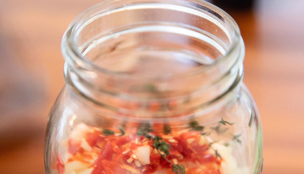 A glass jar filled with fire cider ingredients.