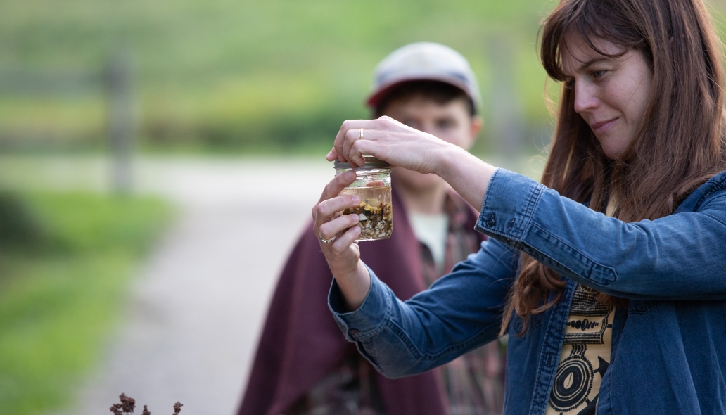 A participant hand tightens a ring lid onto a glass jar filled with chopped up roots and a clear liquid – the makings of a bitter tonic.