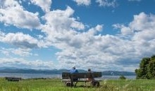 2 people sitting on a bench looking at the lake and sky