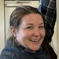 Woman with brown hair pulled back smiles at the camera.