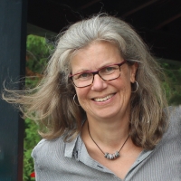 Holly Brough, graying shoulder length hair and glasses