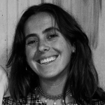 Black and white photo of woman with long dark hair smiling at camera.