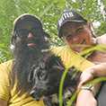 Blair Johnson in sunglasses, hat, and long black beard, with black dog and partner Andi, also in baseball cap